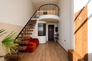 Un interior moderno con una escalera de caracol, un sofá rojo y suelo de madera.