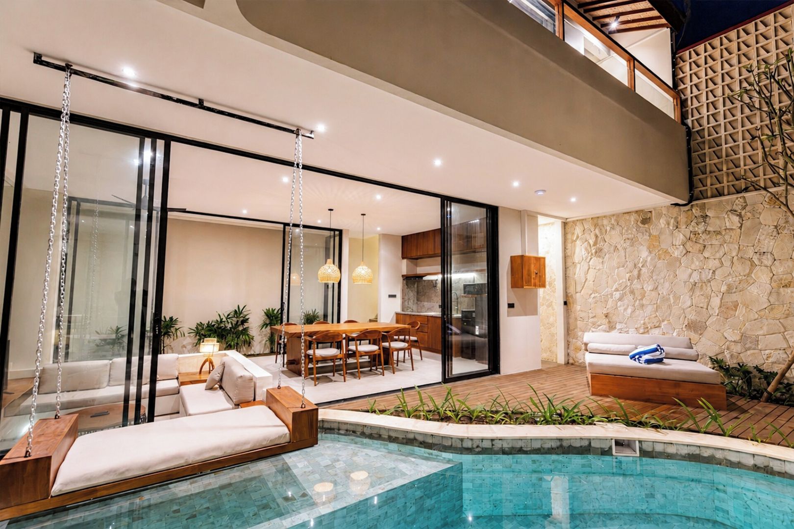 A modern outdoor living space with a pool, a dining area, and a seating area with a sofa and chairs.