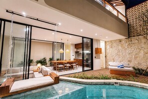 Un espacio exterior moderno con piscina, zona de comedor y área de estar con sofá y sillones.