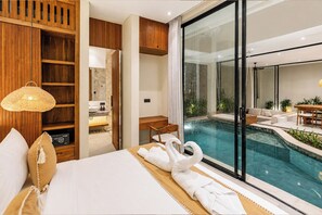 Habitación de hotel con una cama grande, un armario de madera, un baño con lavabo de piedra y vistas a una piscina exterior.