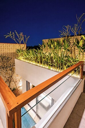 Een modern balkon met glazen hekwerk, een stenen muur en verschillende planten.