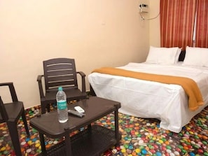 Una habitación de hotel con una cama, una mesa con una botella y una silla.