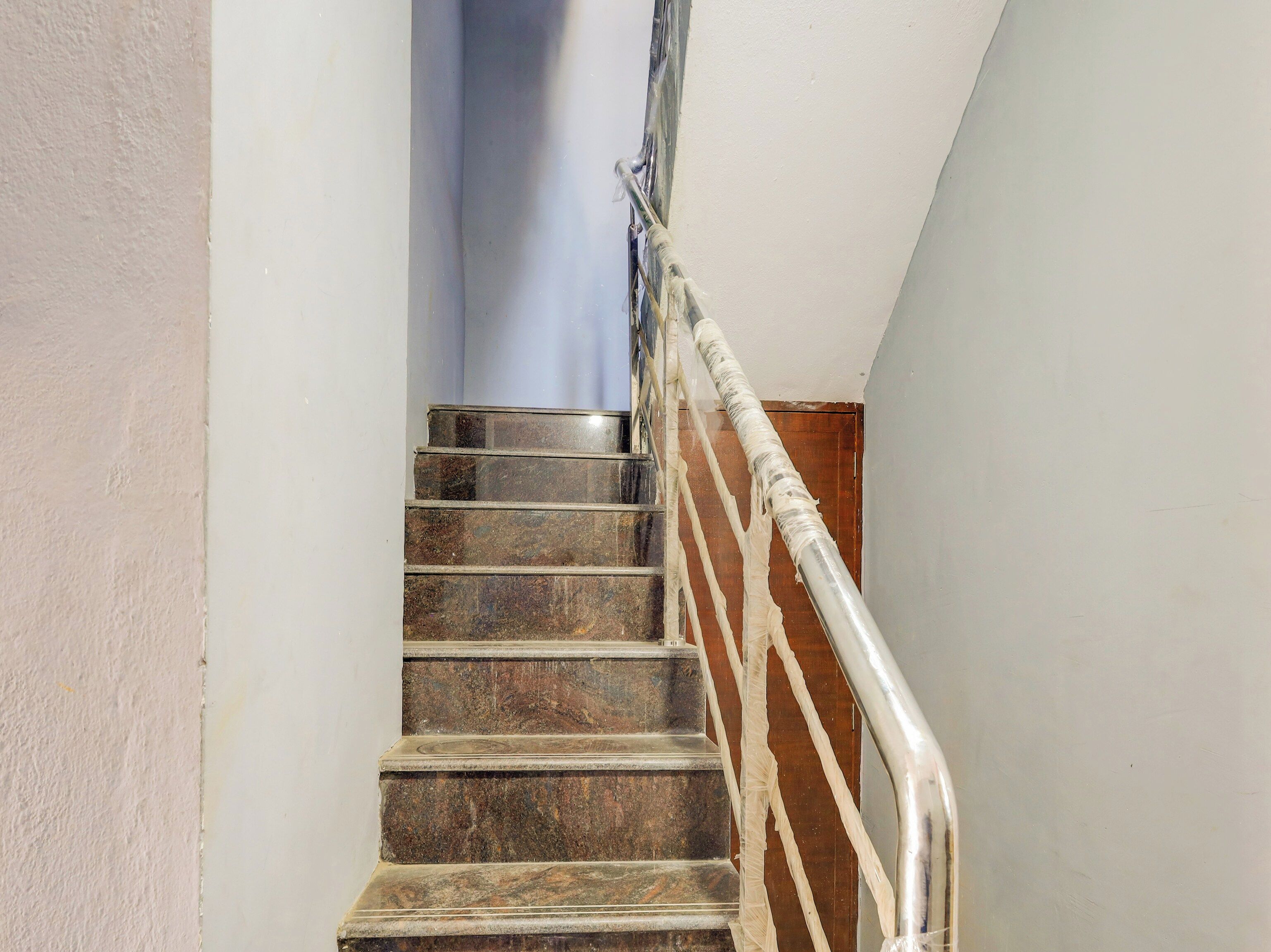 A staircase with a handrail and a wooden door at the top.