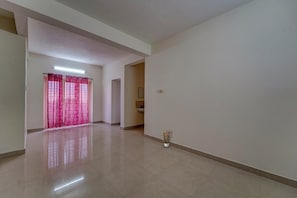 A spacious hallway with a tiled floor, a door with pink curtains, and a small potted plant. - Hotel O Senthamizh Residency (Chennai)