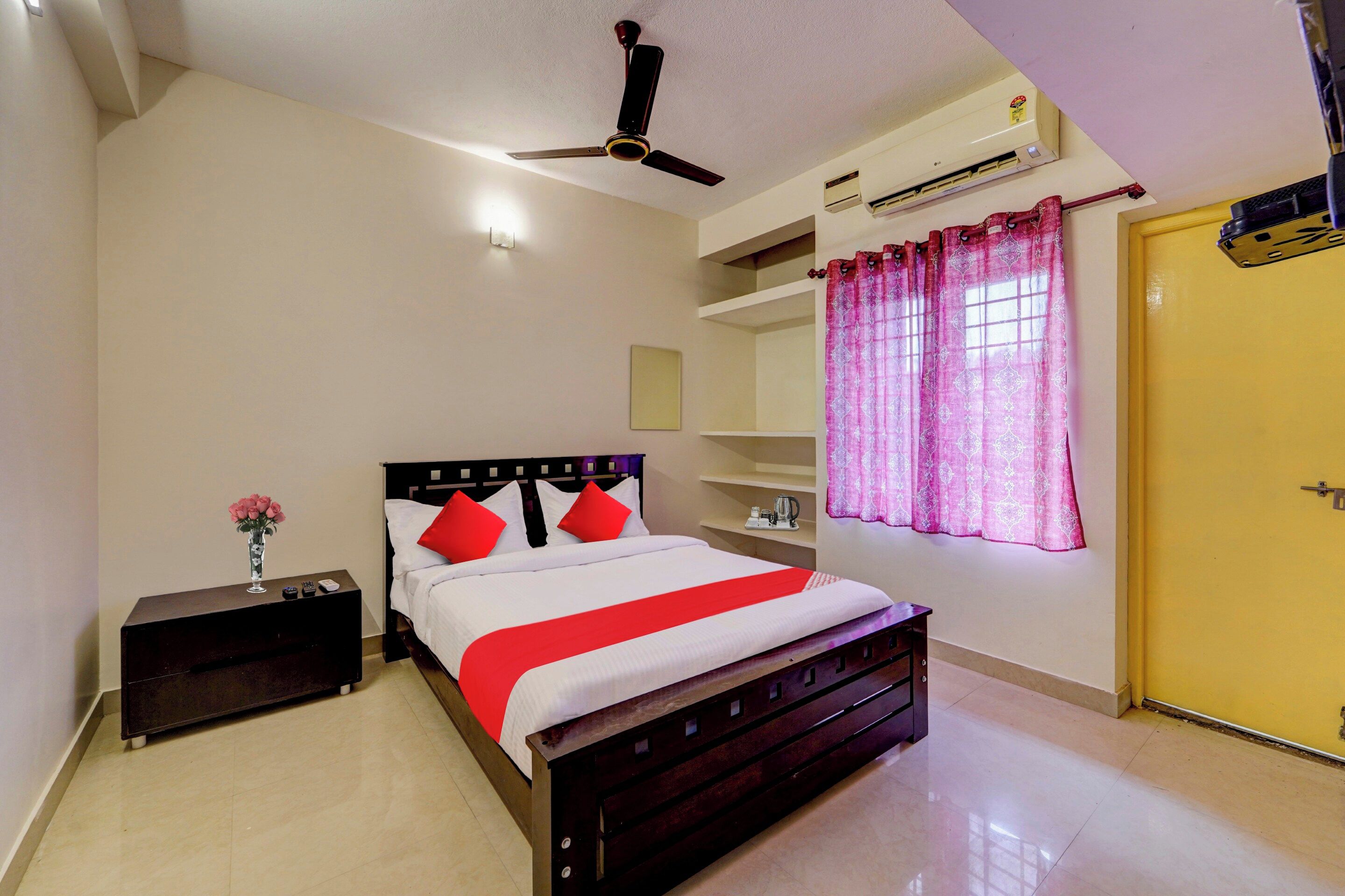A hotel room with a bed, bedside table, nightstand, and a ceiling fan.