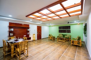 A spacious room with a dining area, a sofa set, and a wooden ceiling with skylight.
