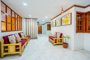 A hallway with two wooden sofas, a potted plant, and framed artwork on the walls.
