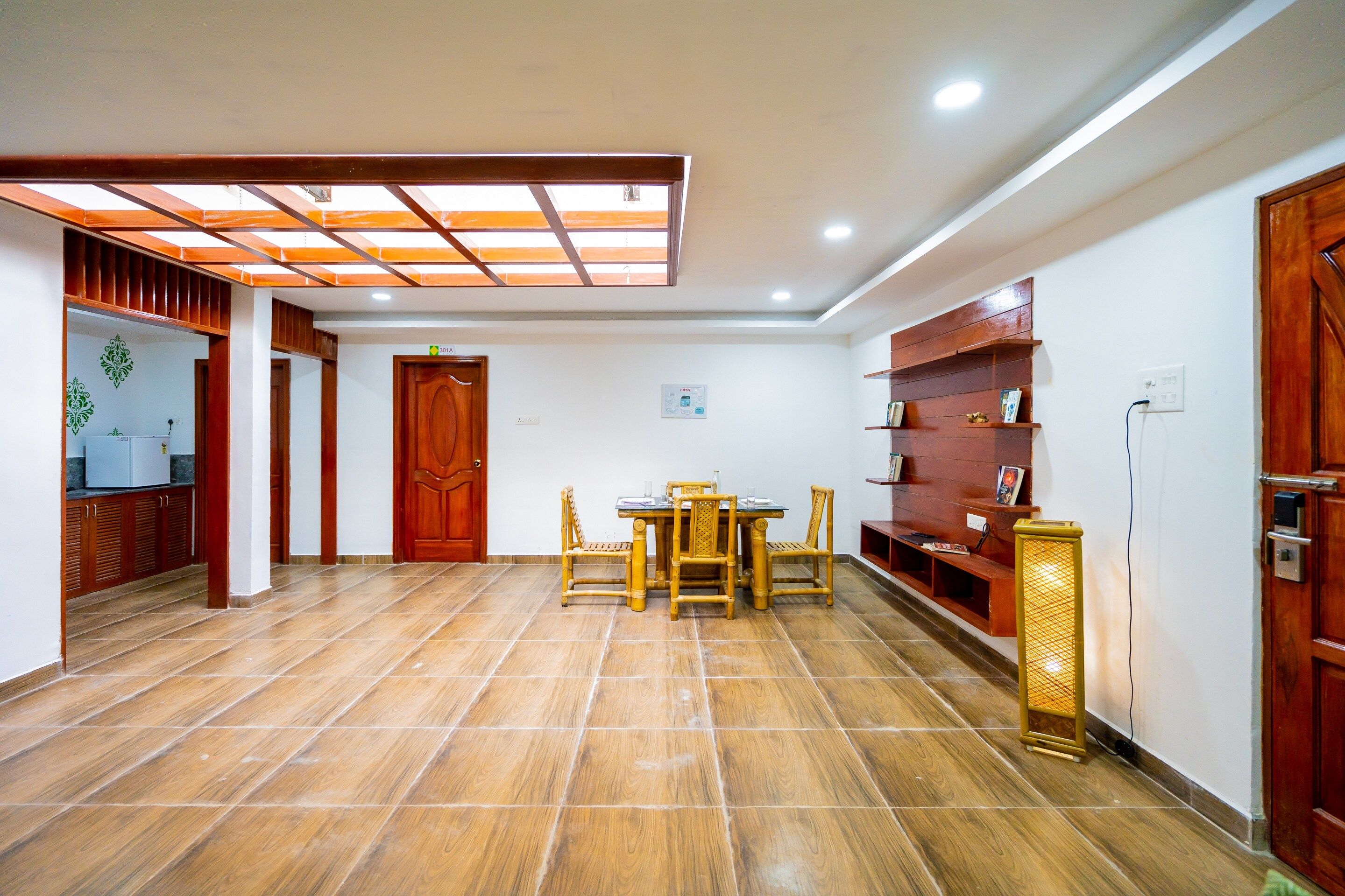 A room with a tiled floor, a wooden door, a table with chairs, and a shelf with books.