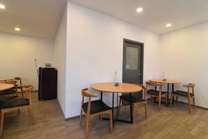 Una habitación con una puerta, un refrigerador y varias mesas redondas con sillas.