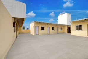 A courtyard with multiple buildings, each with a door and windows, under a clear blue sky. - Hotel O Ramachandra Hospital Porur (Chennai)