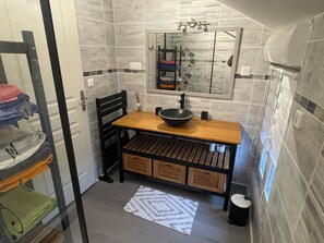 Une petite salle de bain avec un meuble-lavabo en bois, un lavabo noir et un miroir au-dessus.