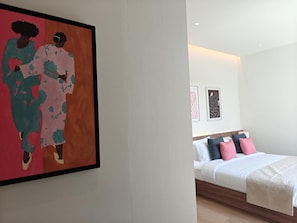 Ein modernes Hotelzimmer mit einem großen Bett, einem Nachttisch und einem Wandbild.