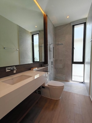 Ein modernes Badezimmer mit einem großen Spiegel, zwei Waschbecken, einer Toilette und einer Dusche.