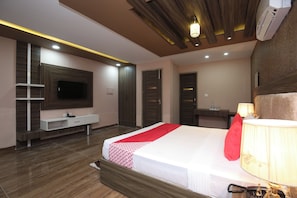 Una camera d'albergo moderna con un letto grande, una TV a schermo piatto, una toeletta con specchio e un soffitto con illuminazione a incasso.
