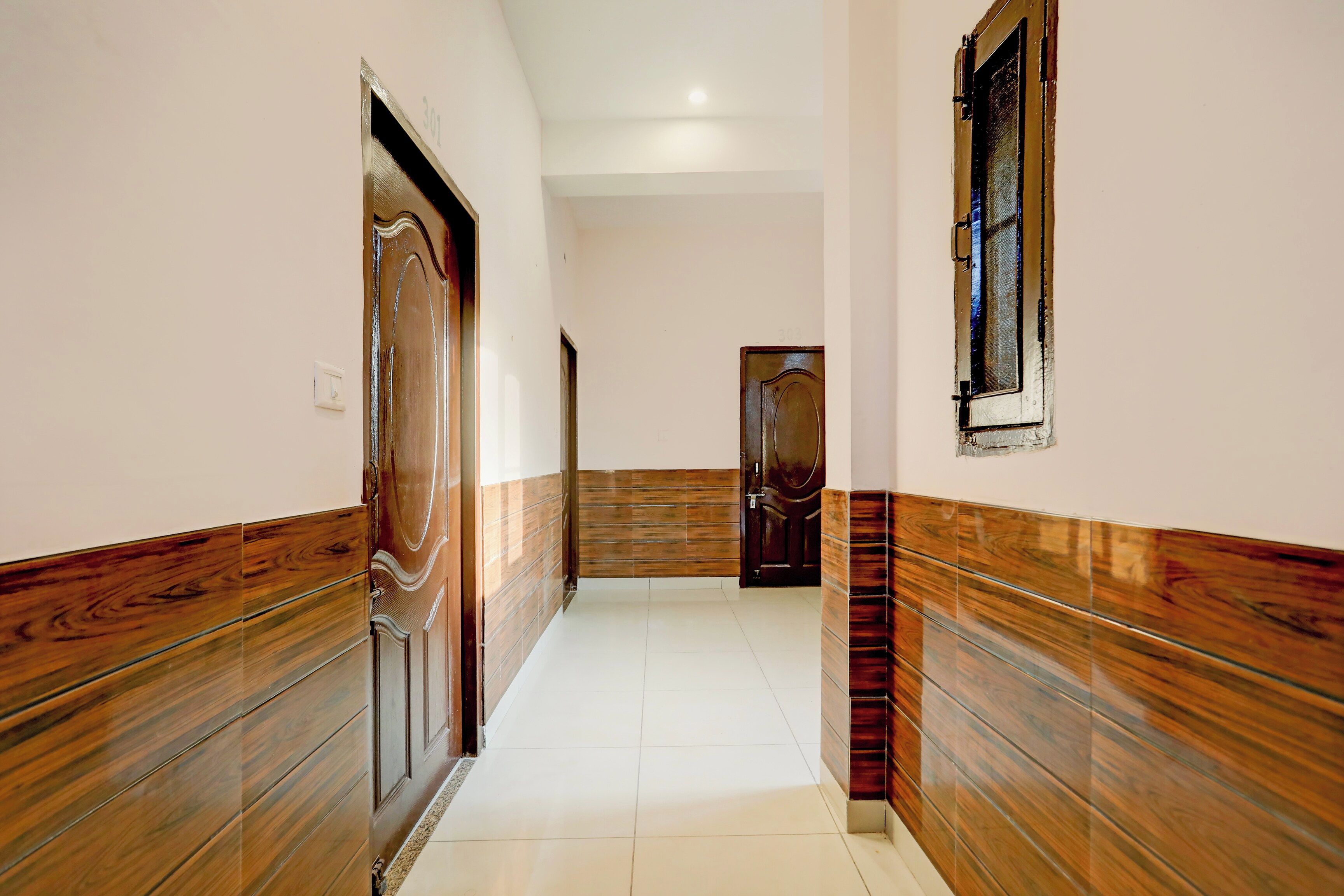 A hallway with wooden paneling on the walls and a tiled floor.
