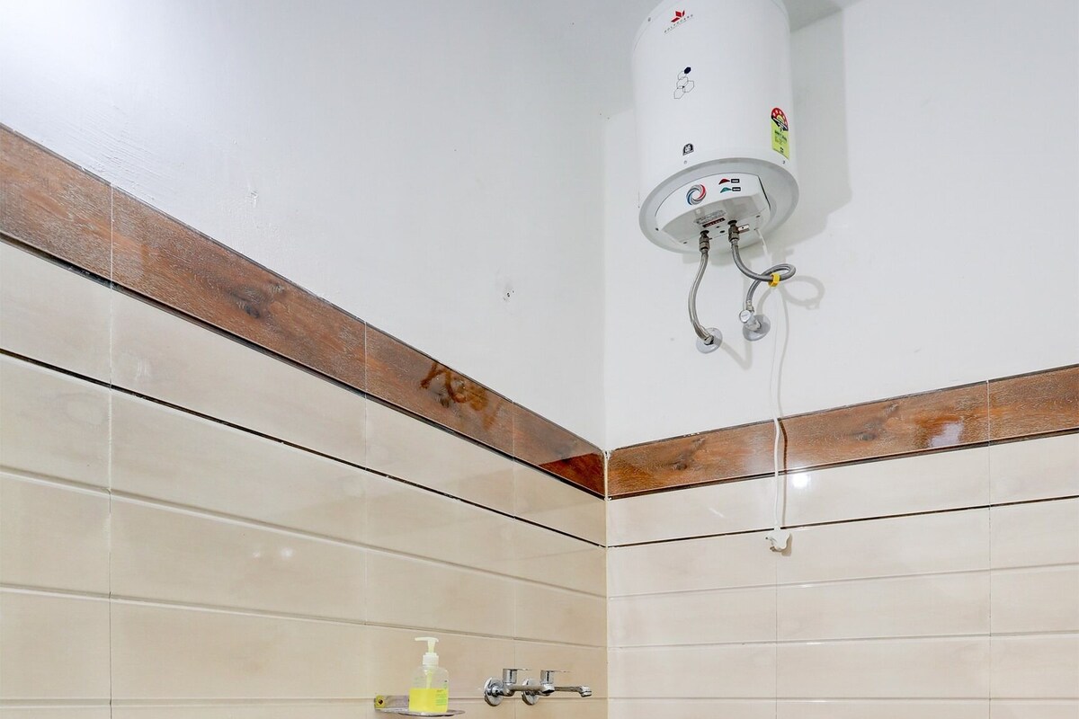 A bathroom with a white sink, a handheld showerhead, and a wall-mounted heater.