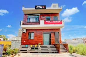 Un immeuble de deux étages avec une enseigne indiquant « Hill View Luxury Rooms & PG ».