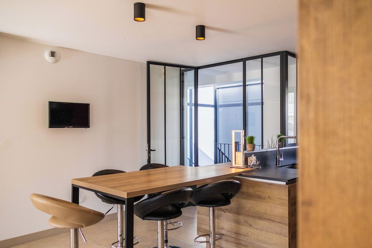 Une cuisine moderne avec un plan de travail en bois, des tabourets de bar noirs et un four encastré.