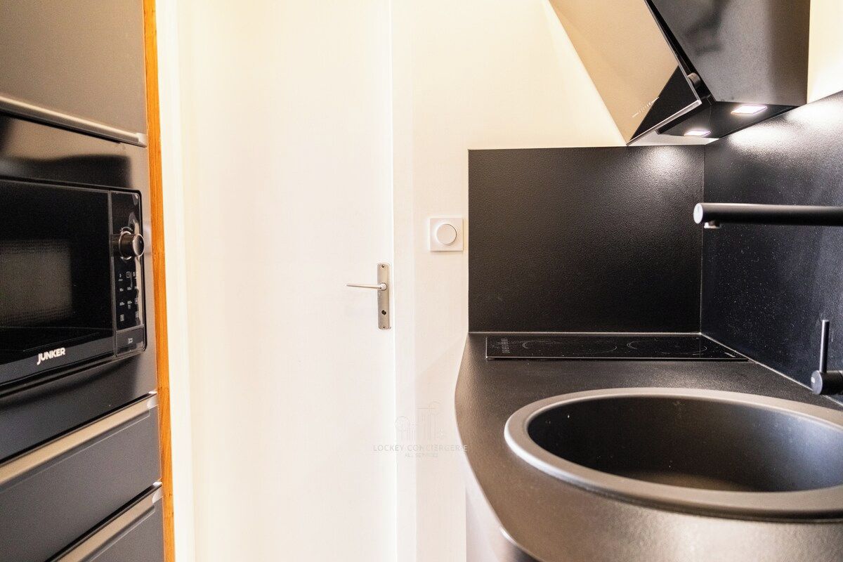 Una cucina moderna con forno a microonde, forno e piano cottura, tutti neri, e un lavandino nero.