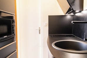 Una cucina moderna con forno a microonde, forno e piano cottura, tutti neri, e un lavandino nero.