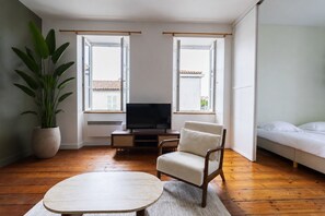 En moderne stue med et fladskærms-tv, en sofa, et sofabord og en potteplante.