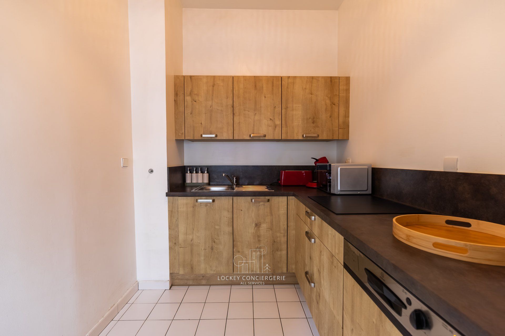 A compact kitchen with wooden cabinets, a black countertop, a sink, a toaster, and a wooden bowl.