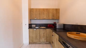 Una cucina compatta con mobili in legno, un piano di lavoro nero, un lavello, un tostapane e una ciotola di legno.