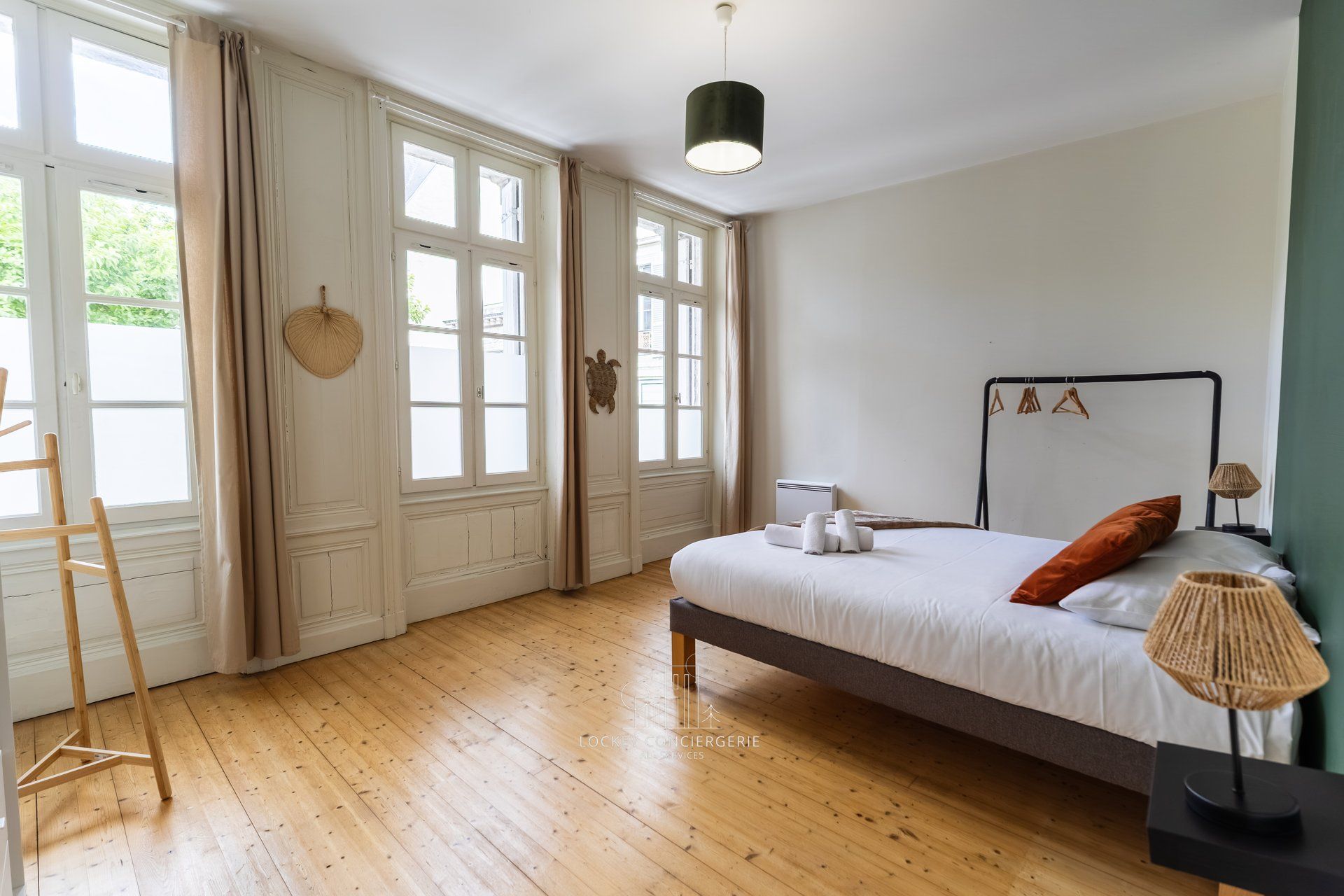 A bedroom with a bed, a standing lamp, and a window with curtains.