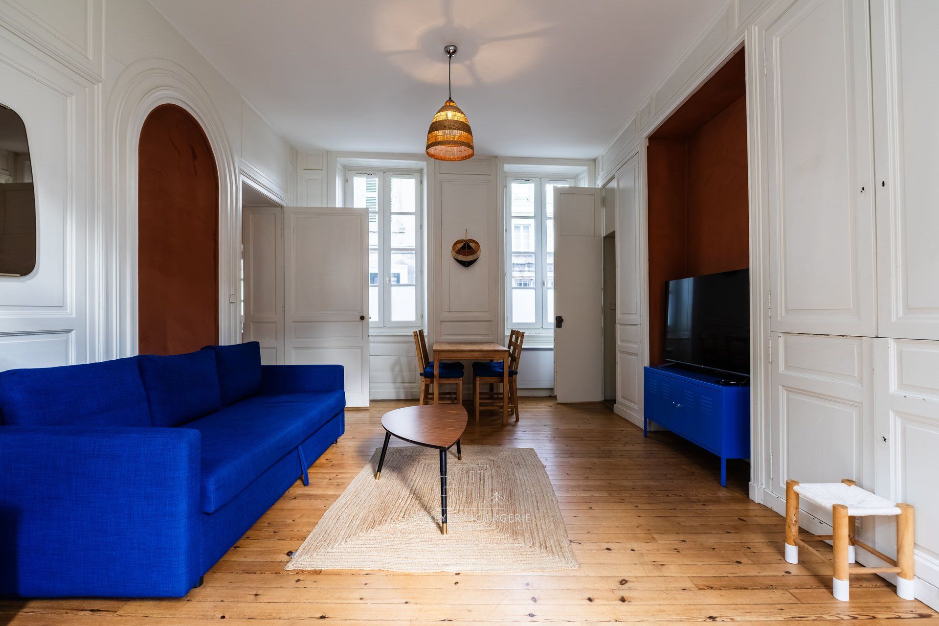 Un soggiorno con un divano blu, un tavolo da pranzo in legno e una televisione.