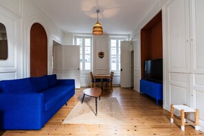 Un soggiorno con un divano blu, un tavolo da pranzo in legno e una televisione.
