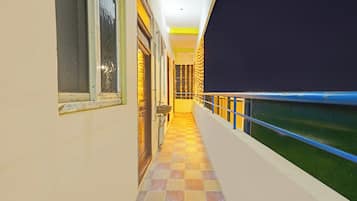 A corridor with a checkered floor, a window with a Venetian blind, and a wall with a decorative pattern.