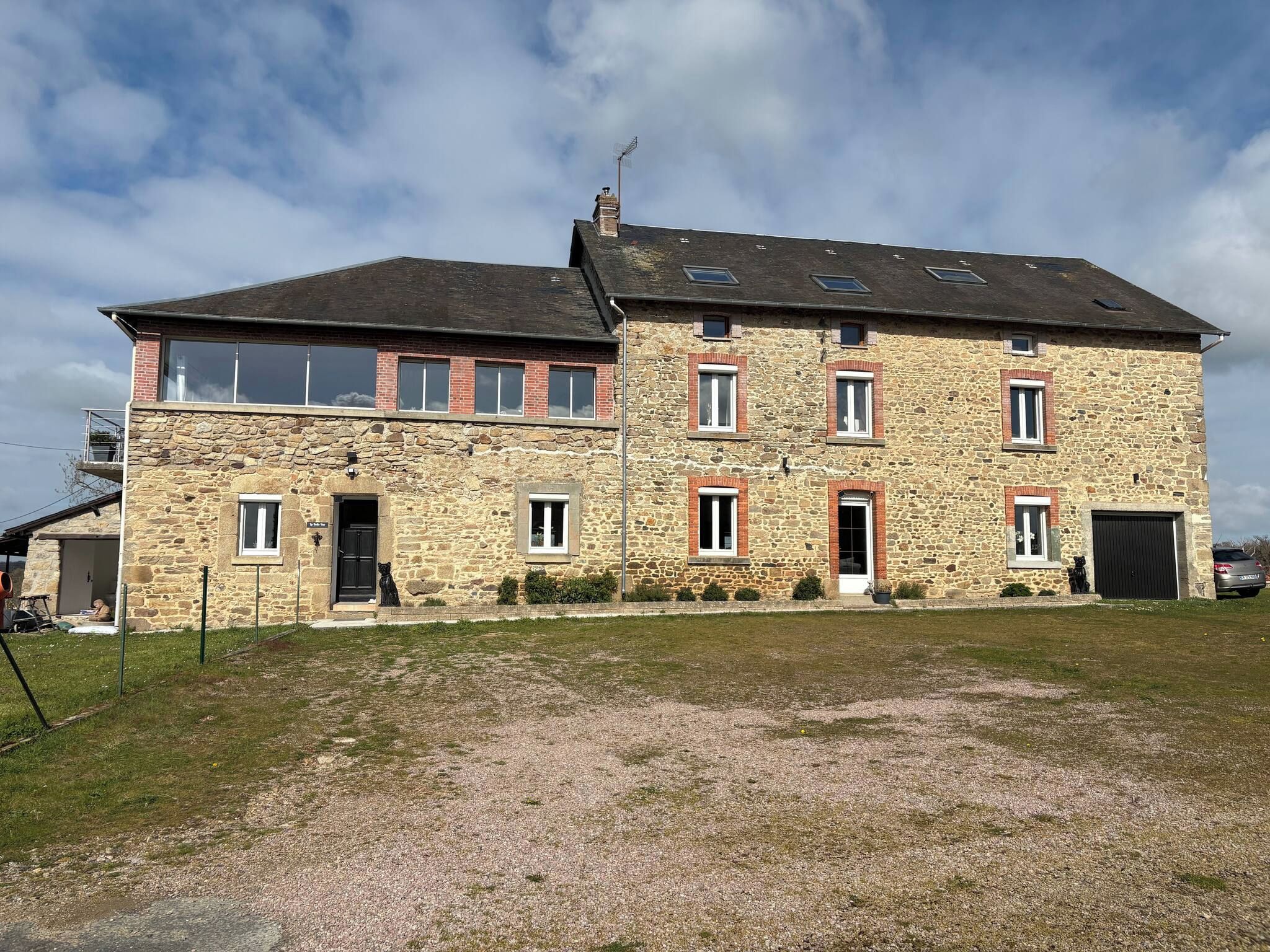 A two-story stone building with multiple windows and a gravel driveway.