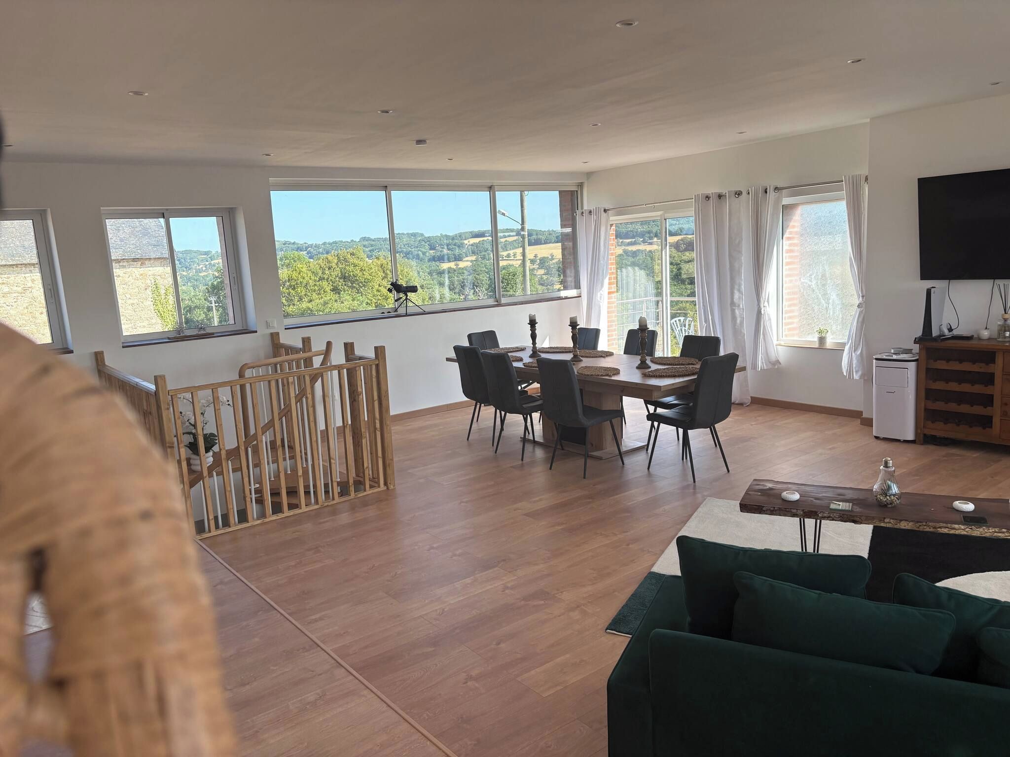 Een ruime woonkamer met een eettafel, stoelen, een bank en een televisie.