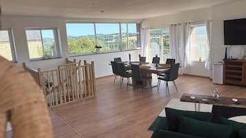 Een ruime woonkamer met een eettafel, stoelen, een bank en een televisie.