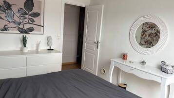 A bedroom with a bed, a dresser, a mirror, and a painting on the wall.