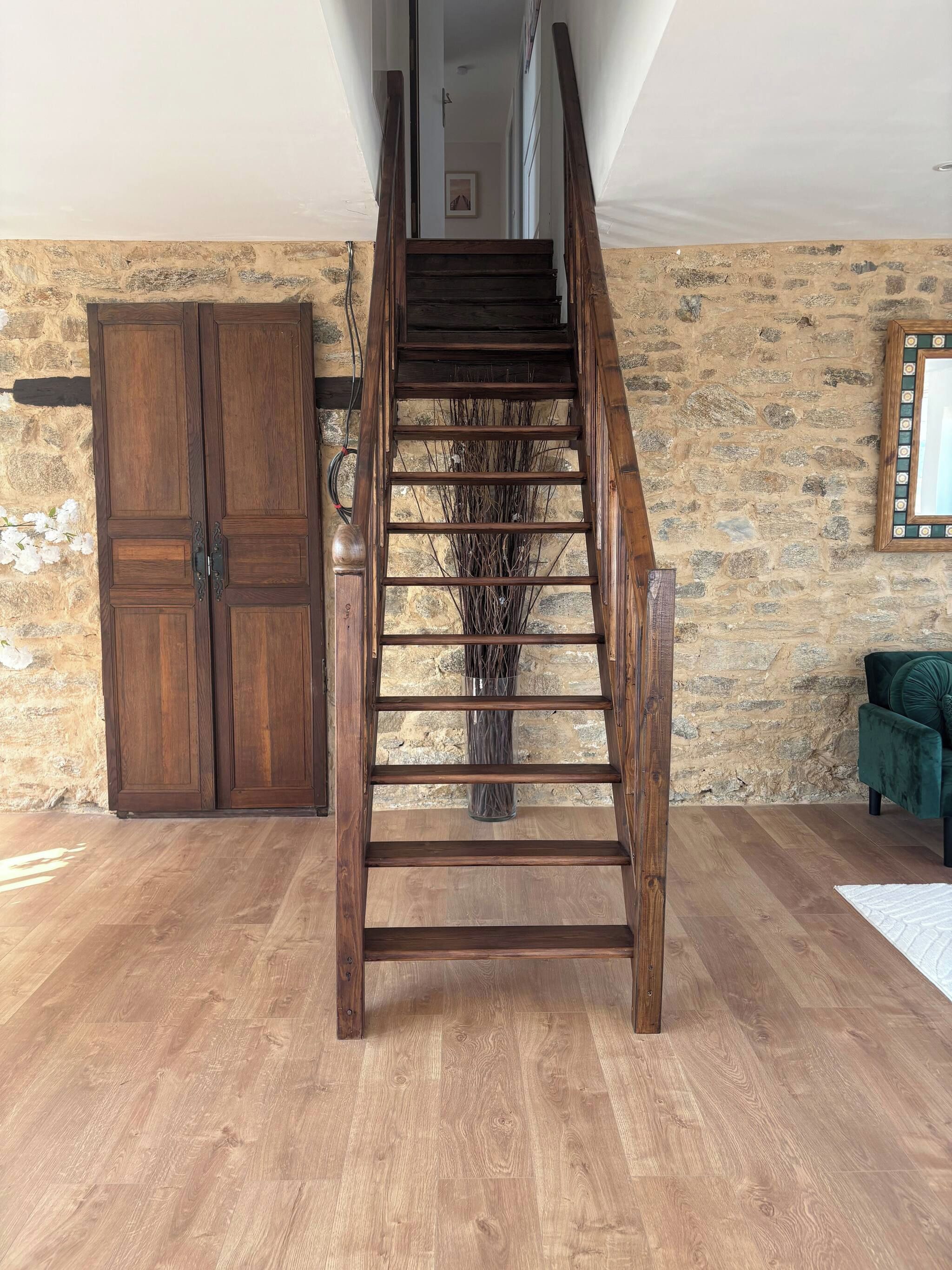 Una scala in legno con una parete in pietra e un divano verde.