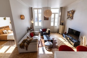 Ein helles Wohnzimmer mit einer Couch, einem Couchtisch, einem Fernseher und einem Kamin.