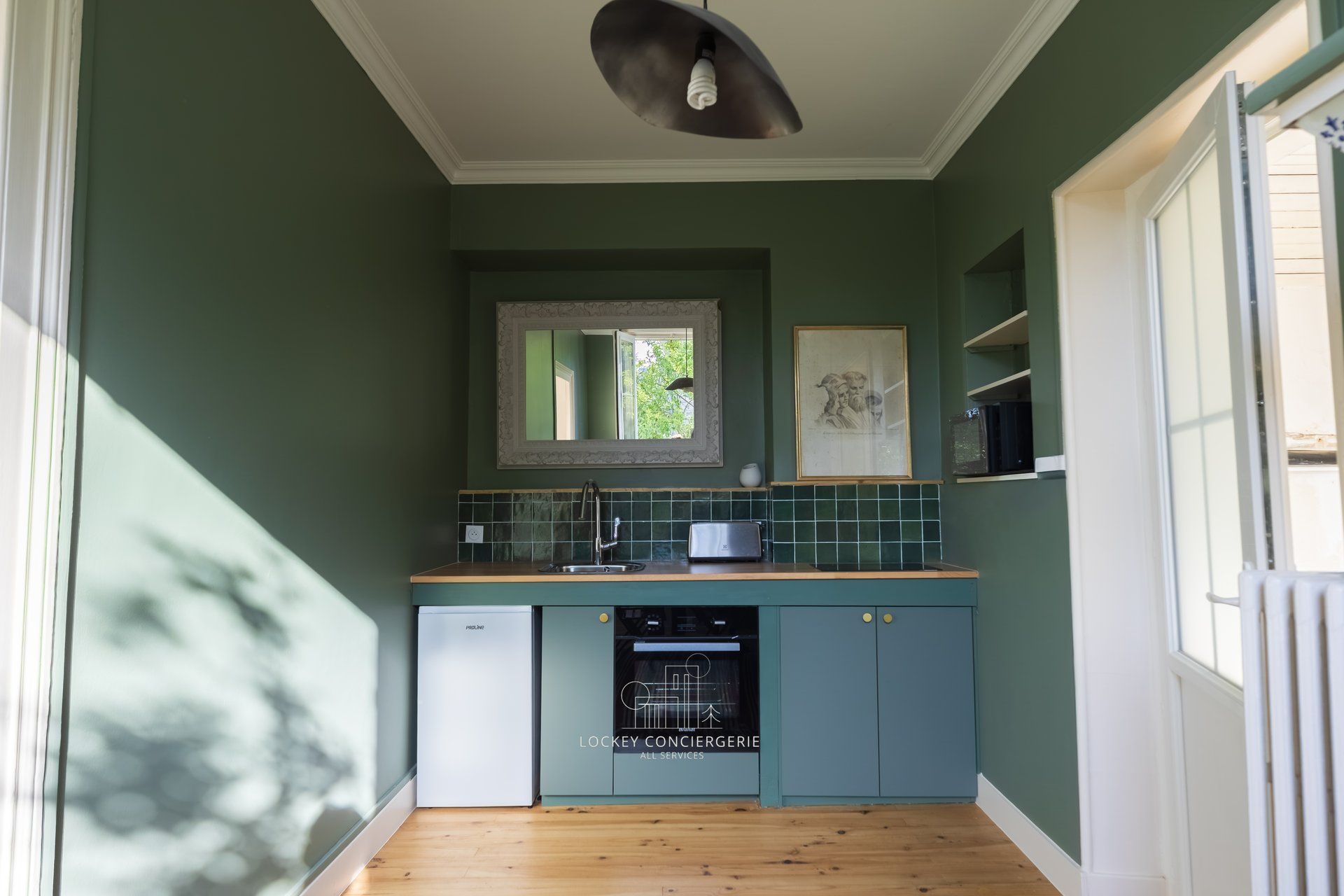 Una cocina compacta con lavavajillas incorporado, ventana sobre el fregadero y puerta que da a un comedor.