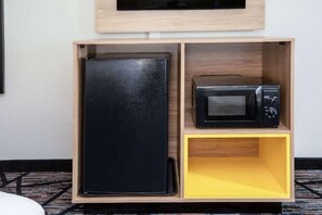 Un gabinete de madera con un refrigerador negro y un microondas encima.