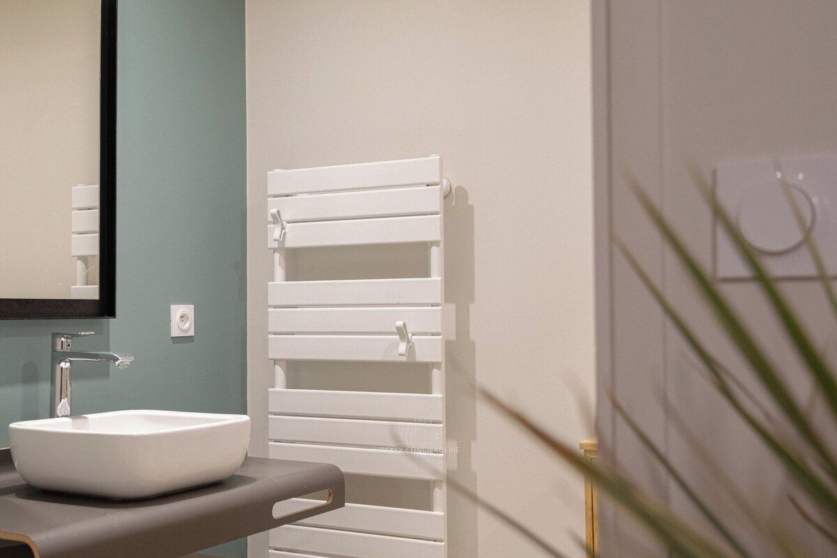 Une salle de bain avec un lavabo blanc, un miroir et un porte-serviettes.