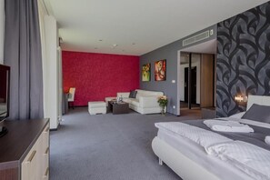 A hotel room with a large bed, a sofa, a coffee table, and a TV. - Hotel TENIS (Zvolen)