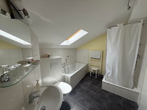 Ein modernes Badezimmer mit Oberlicht, Badewanne, Dusche und Toilette.