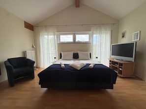 Ein Schlafzimmer mit einem Bett, einem Sessel, einem Fernseher und einem Fenster.