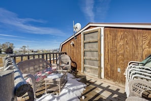 Une terrasse en bois, meublée de meubles en osier, et un sol recouvert de neige.
