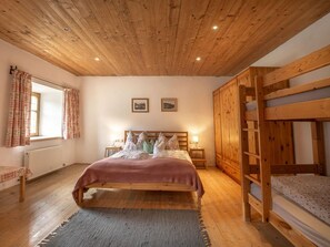 Ein Schlafzimmer mit Holzboden, einem Bett, einem Etagenbett und einem Fenster mit Vorhängen.