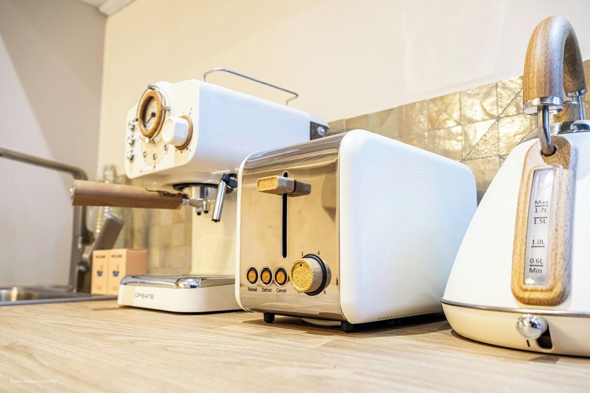 Une cuisine équipée d’une machine à café, d’un grille-pain et d’un appareil à pain, le tout posé sur le plan de travail.