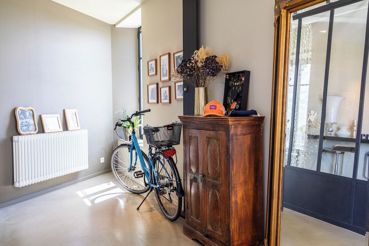 Un couloir avec un radiateur, un vélo, une armoire et des tableaux encadrés accrochés au mur.