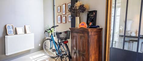 Un couloir avec un radiateur, un vélo, une armoire et des tableaux encadrés accrochés au mur.