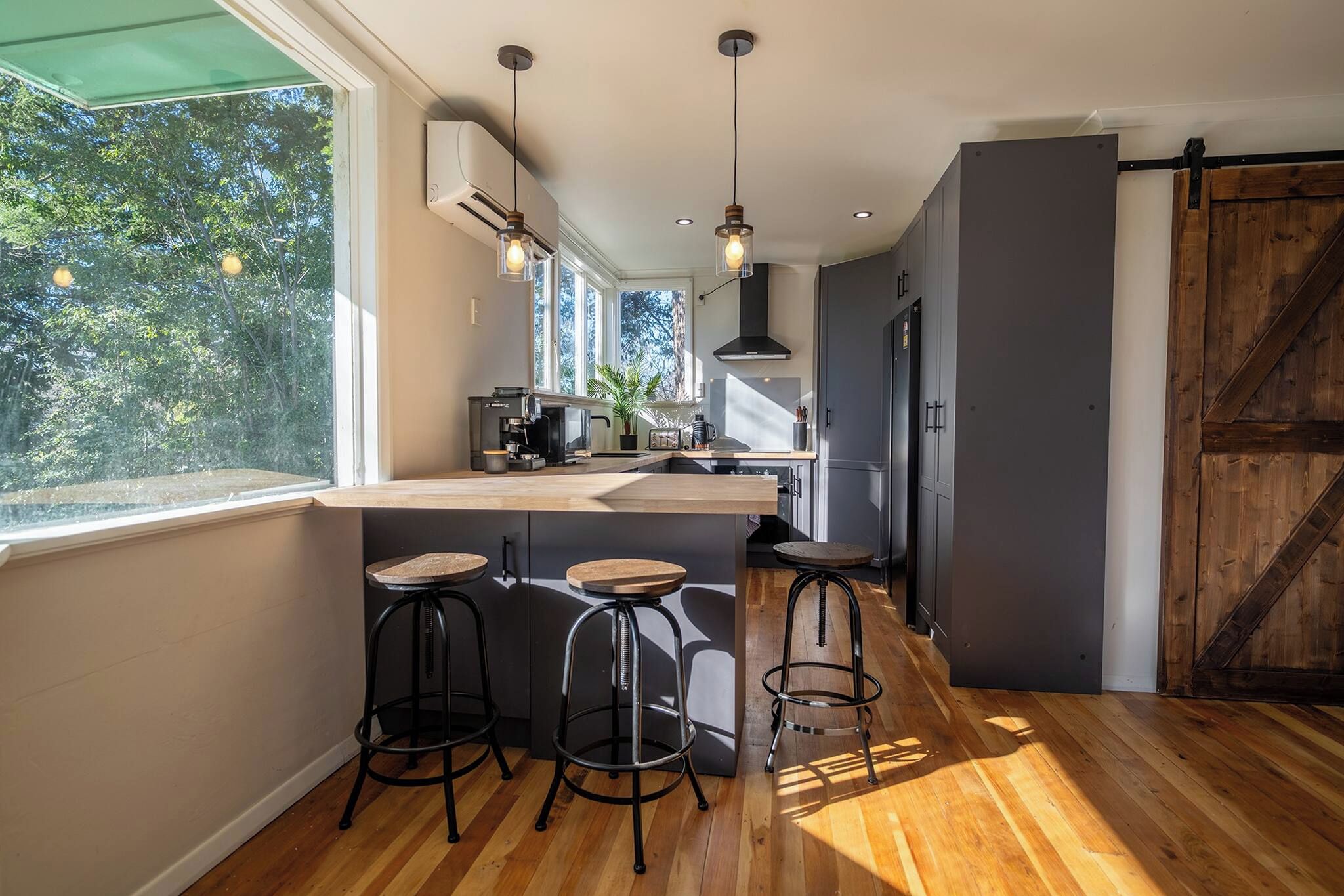 Une cuisine moderne avec un coin bar, un plancher en bois et de grandes fenêtres.