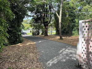 A gravel pathway flanked by trees and a wooden fence. - The Jumping Trout Rustic Hideaway (Tūrangi)
